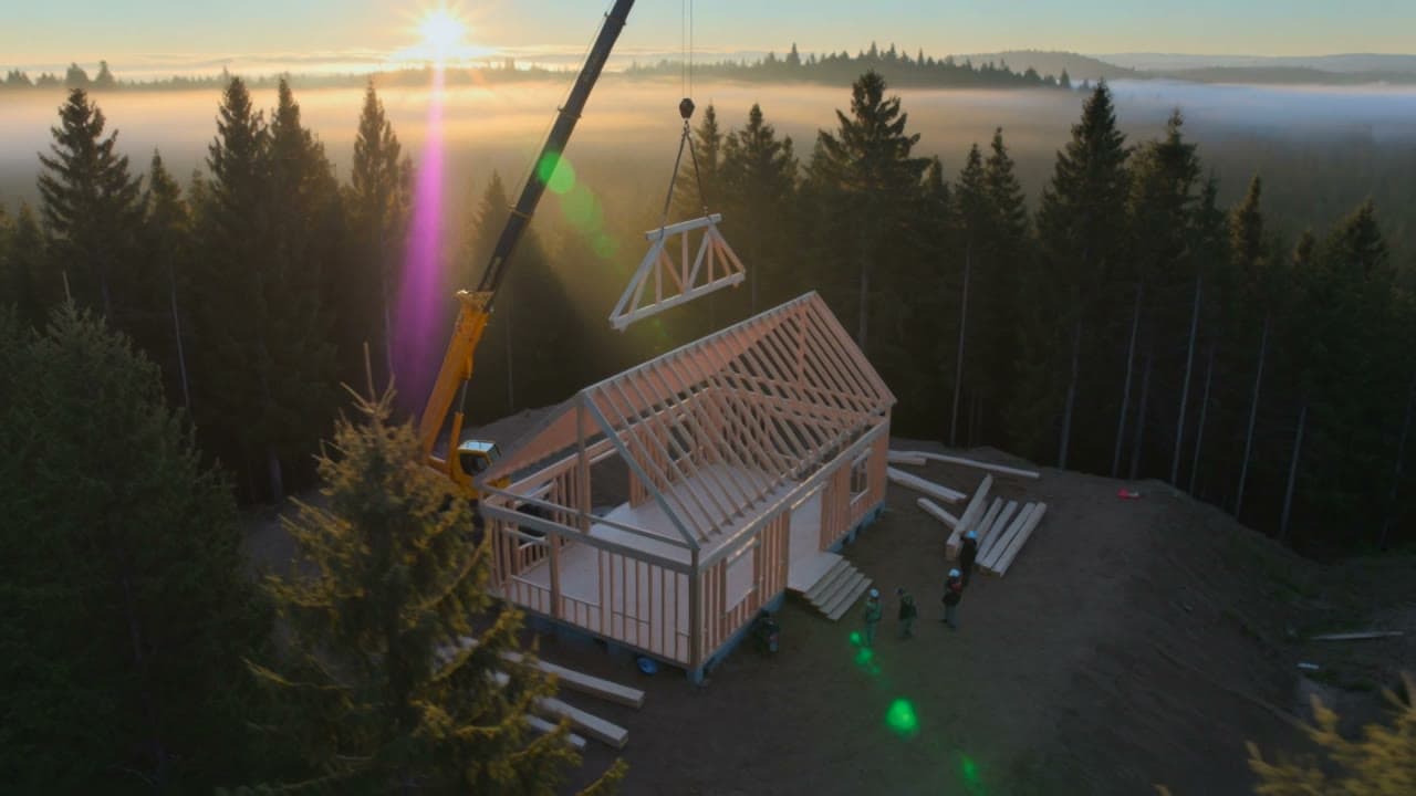 Wood structure being erected, a roof truss lifted by a crane