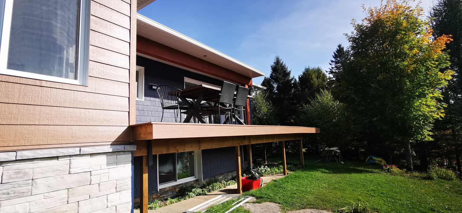 Détail de jonction entre pierre, bois et bardeau sur une façade